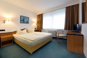 ein Hotelzimmer mit einem Bett und einem Stuhl in der Unterkunft LAT Hotel & Apartmenthaus Berlin in Eisenhüttenstadt