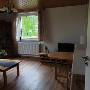 salon z drewnianym stołem i oknem w obiekcie FeWo Zimmermann w mieście Etterwinden