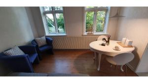 a room with a table and chairs and two windows at The Cherry Apartment - 'Den Gule Svane' Guest House near Rønne & Beach in Rønne