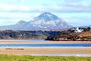 a mountain looms over a body of water with a mountain at Luí na Gréine in Gweedore