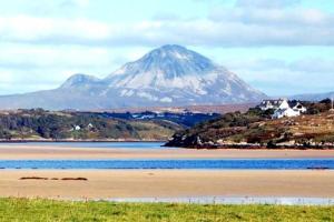 una montaña se cierne sobre un cuerpo de agua con una montaña en Luí na Gréine en Gweedore