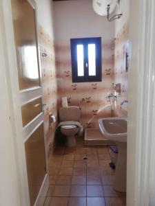 カシオピにあるDimitrakis Apartmentsのバスルーム(トイレ、洗面台付)、窓が備わります。