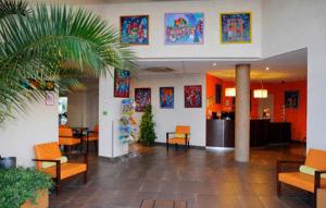 a lobby with chairs and tables in a building at The Originals Boutique, Actuel H&ocirc;tel, Saint-Etienne A&eacute;roport in Andr&eacute;zieux-Bouth&eacute;on