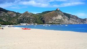 a beach with boats in the water and mountains at La Sirena Appartamento in Oliveri +6 photos