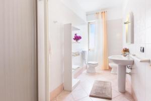 a white bathroom with a sink and a toilet at Il Canestro Sardo in Cagliari