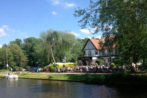 a crowd of people standing around a building next to a river at The Weir Hotel in Walton-on-Thames