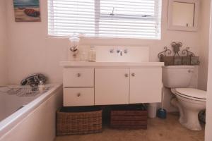 a bathroom with a sink and a toilet and a window at Pringle Beach House in Pringle Bay