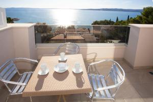 a table and chairs on a balcony with a view of the ocean at Apartments Medvidovic in Baška Voda