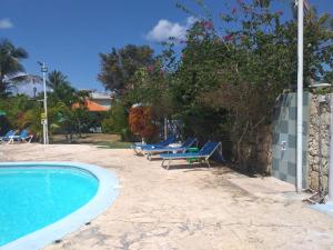 a swimming pool with lounge chairs next to a wall at Hotel Residence Eden in Bayahibe