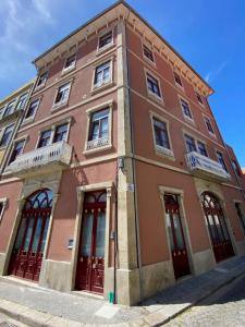 un bâtiment marron avec des portes rouges dans une rue dans l'établissement Porto.Leça - Studios and Apts (Apt D), à Leça da Palmeira