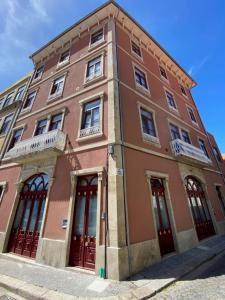 um edifício castanho com portas vermelhas numa rua em Porto.Leça - Studios and Apts (Apt D) em Leça da Palmeira