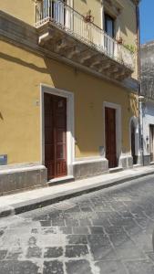 a yellow building with two doors and a balcony at i 2 Capitani in Riposto