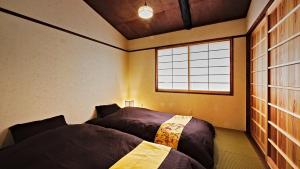 1 dormitorio con 2 camas y ventana en Kokonoe Machiya en Kyoto