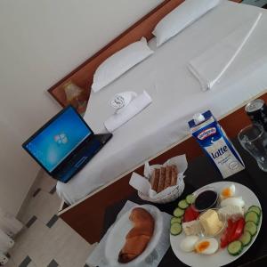 ein Hotelzimmer mit einem Laptop auf einem Tisch mit Essen in der Unterkunft Vila 57 HOTEL in Tirana