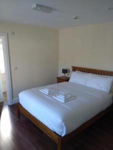 um quarto com uma cama branca e toalhas em Brackloon Lodge-Brackluin em Anascaul