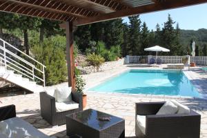 a swimming pool with chairs and a table and an umbrella at Villa Paparouna in Magaziá