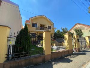 a yellow house with a fence in front of it at Alexia Rooms in Oradea