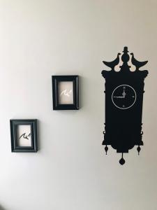 a black clock on a wall with three pictures at BB House Budget & Boutique in Chiang Mai
