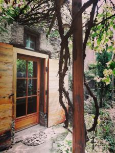 una puerta a una casa con un árbol al lado en Gîte Sainte Croix en Jarez, Le Val des Equins en Sainte-Croix-en-Jarez