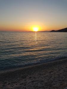 a sunset on a beach with the sun setting over the water at Apartments Garac in Dugi Rat
