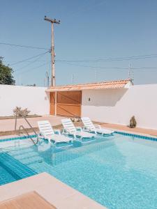 una piscina con sedie bianche e una piscina di Mansão Beberibe a Beberibe