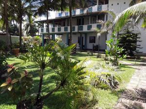 a building with palm trees in front of it at Karl Holiday Bungalow in Kalutara