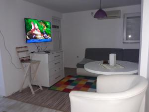 ein Wohnzimmer mit einem Sofa und einem TV an der Wand in der Unterkunft APARTMAN BUKULJA 2 in Aranđelovac