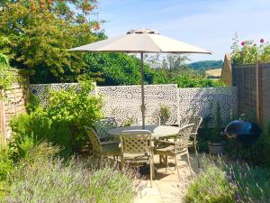 uma mesa e cadeiras com um guarda-sol num jardim em Pearl Cottage em Blockley