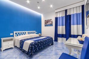 um quarto azul com uma cama e uma secretária em Hotel Metropole em Sorrento