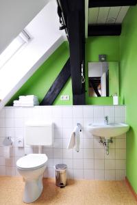 a green bathroom with a toilet and a sink at Suite „Niedersachsen“ - wunderschönes Apartment in Fachwerkhaus in Hannover