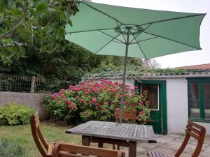 une table en bois avec un parasol et deux chaises dans l'établissement Maison à deux pas de la mer, à Wimereux