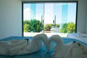twee witte zwanen zitten op twee bedden in een kamer bij Pousada Porto Sol in Porto De Galinhas