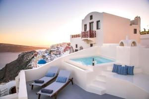 a pool on the side of a building with chairs at Aloia Villas in Oia