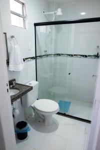 a bathroom with a toilet and a glass shower at Pousada Porto Sol in Porto De Galinhas