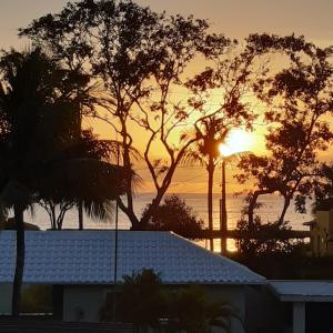 a sunset over the ocean with palm trees and a house at Areia do Atlantico Hotel in Porto Seguro