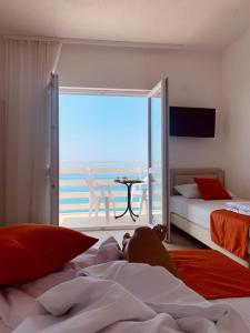 a person laying on a bed in a bedroom with a view at Jelić apartmani in Sutomore