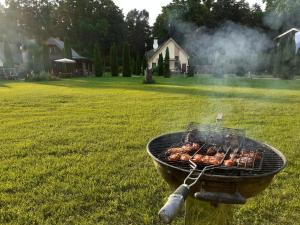 a grill in a yard with chickens cooking on it at Forest Edge Lodge in Rīga