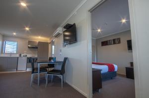 Habitación con cama, mesa y sillas. en Amity Court Motel en Stratford