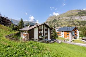ein Haus auf einem Hügel mit Bergen im Hintergrund in der Unterkunft Ferienwohnung Haus Mia in Zermatt