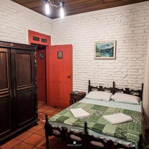 um quarto com uma cama e uma porta vermelha em Eco Pousada Passaredo em São Miguel Arcanjo