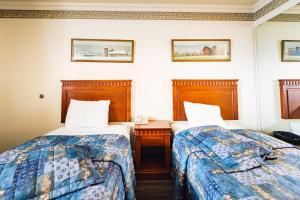 Cette chambre d'hôtel comprend 2 lits, une table de chevet et 2 lits. dans l'établissement Auberge Harris, à Saint-Jean-sur-Richelieu