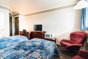 um quarto de hotel com duas camas e uma cadeira e uma secretária em Auberge Harris em Saint-Jean-sur-Richelieu