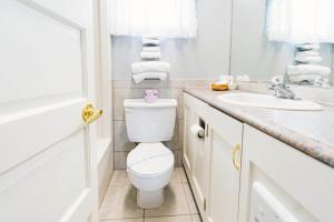 La salle de bains blanche est pourvue de toilettes et d'un lavabo. dans l'établissement Auberge Harris, à Saint-Jean-sur-Richelieu