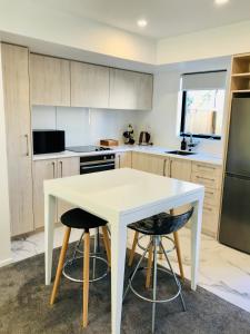 a kitchen with a white table and two stools at New Townhouse 5 min from central CHCH including bikes to use in Christchurch