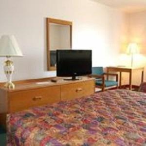 a hotel room with a bed and a flat screen tv at Country Haven Inn in Hillsboro