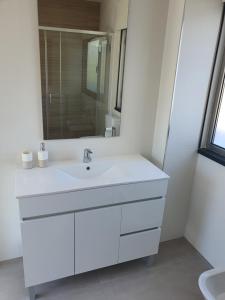 Un baño blanco con lavabo y espejo. en Figueira Beach Apartment, en Buarcos 13 fotos más