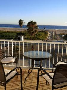 a table and chairs on a deck with the beach at Apartamento Dos Faros in Conil de la Frontera
