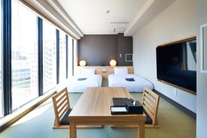 ein Hotelzimmer mit 2 Betten und einem Tisch mit Stühlen in der Unterkunft HOTEL Enmichi in Kawasaki