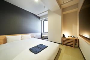 a bedroom with a bed with a blue towel on it at HOTEL Enmichi in Kawasaki