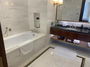 un bagno bianco con vasca e lavandino di Ordos Yonggui Hotel a Ordos